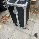 Černý transportní case s hliníkovými hranami a rohovými zpevněními. Na horní straně jsou dvě kovové madla a vyjímatelný teleskopický vozík s koly. Po…