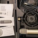 Sada obsahuje stříbrný kondenzátorový mikrofon s nápisem Made in Australia, černý pavoukový držák a černý XLR kabel. Součástí jsou tři papírové dokum…
