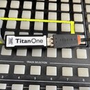 Na černém podkladu s bílými tlačítky a nápisy TRACK SELECTION, STOP ALL CLIPS a číslováním 2–8 MASTER leží USB adaptér. Adaptér je černý s bílým nápi…