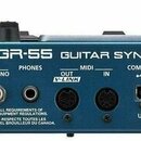 Zadní strana modrého kytarového syntetizátoru s nápisem Roland GR-55 GUITAR SYNTHESIZER. Jsou zde viditelné konektory označené jako GK IN, GUITAR OUT…