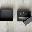 Na fotografii jsou dvě černé krabičky na šedém podkladu z laminátu. V pravé krabičce je umístěno malé černé zařízení s nápisy Power a USB-C, doprováz…