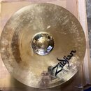 Zlatavý kovový činel s viditelným broušením povrchu. Na ploše je černý nápis Zildjian. Povrch vykazuje drobné škrábance a stopy používání.