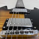 Elektrická kytara s tělem v žlutém gradientu a černým pickguardem. Nástroj má dva chromované humbuckery a chromovaný kobylník. Na fotce nejsou žádné…