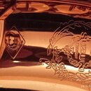 Detail zlatavého, lesklého kovového povrchu hudebního nástroje. V pravé části je vyryté logo SUZUKI a nápis MUSIQUE obklopený věncem z listí. V levé…