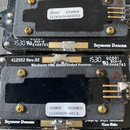 Fotografie zachycuje dvě černé elektronické součástky (preampy) značky Seymour Duncan. Horní kus má nápisy 412551 Rev.03, Designed by Kevin Beller a…