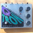Kytarový efekt v kovovém šasi s nápisem Q TRON a textem Envelope Controlled Filter. Na přední straně jsou čtyři ovládací knoflíky s popisky Peak, Gai…