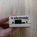 Bílá kytarový ladič s nápisy tc electronic, in, out a polytune. Na zadní straně jsou dva vstupní konektory a jeden USB port. Povrch v levé části u lo…