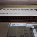 Bílá rytmická doprovodovka s nápisem RHYTHM COMPOSER TR-626. Horní panel obsahuje řadu béžových tlačítek a ovládacích prvků. Na zadní straně jsou umí…