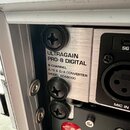Detail rackového zařízení v hliníkovém case. Na stříbrném předním panelu je černý nápis ULTRAGAIN PRO-8 DIGITAL, 8-CHANNEL A/D & D/A CONVERTER MODEL…