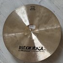 Zlatavý kovový činel s viditelným broušením povrchu. Na spodní straně je černý nápis istanbul Mehmet Handmade Cymbals Frum Turkey a v horní části ští…