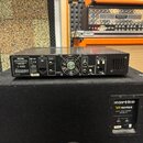 Na černém basovém reproduktoru Hartke VK-series VX410 BASS CABINET 400 WATTS stojí černý zesilovač. Na zadní straně zesilovače je vidět nápis Hartke…
