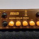 Hnědý basový zesilovač s nápisem Little Mark Tube a logem Markbass. Přední panel obsahuje několik černých ovládacích knoflíků, pět žlutých otočných p…