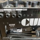 Zadní strana černého kytarového komba s bílým nápisem CUBE. Jsou zde viditelné konektory RECORDING OUT/PHONES, FOOT SW a AUX IN. Na štítku je uveden…