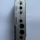 Zadní strana stříbrného elektronického zařízení s nápisy YAMAHA a QY100. Jsou zde viditelné konektory s popisky LINE OUT/PHONES, DC IN, GAIN, GUITAR/…