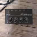 Černý sluchátkový zesilovač s nápisy behringer, Micro AMP HA400 a ULTRA-COMPACT 4-CHANNEL STEREO HEADPHONE AMPLIFIER. Zařízení má čtyři regulační kno…