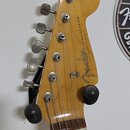 Hlava elektrické kytary z přírodního dřeva s šesti kovovými ladičkami. Na povrchu je černý nápis Fender a STRATOCASTER, dále malý nápis MADE IN USA S…