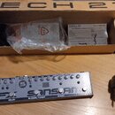 Kytarový efekt pedál stříbrné barvy s nápisy TECH 21, FLY RIG a EFX SANSAMP. Na horní straně jsou ovládací knoflíky, přepínače a nápisy jako REVERB,…