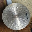 Kovový činel s výrazným kmitavým povrchem a četnými hlubokými důlky (hammerování). Na pravé straně je čitelné logo Zildjian. Činely stojí na kovovém…