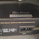 Detail zadní strany černého elektronického zařízení s napájecím konektorem a pojistkovým pouzdrem. Na stříbrném štítku je nápis Mesa/Boogie, pod ním…