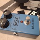 Modrý kytarový efekt s nápisy MXR a blue box. Na horní straně jsou dva černé otočné knoflíky s popisky BLEND a OUTPUT, červená kontrolka a kovový spí…