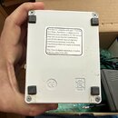 Bílá kovová krabička s textem na nálepce: „This device complies with part 15 of the FCC Rules. Operation is subject to the following two conditions:…
