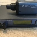 Na fotografii je šedý bezdrátový přijímač a vysílač značky SENNHEISER. Na vysílači je nápis SKP 500 G2 a na přijímači TRUE DIVERSITY RECEIVER GW 500…