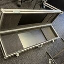 Otevřený transportní kufr z hliníkových profilů s černým povrchem. Vnitřek je vyložen šedou plstí a obsahuje vylisovanou výplň pro instrument. Na kuf…