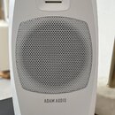 Bílý studiový reproduktor s kovovou mřížkou přes membránu. V horní části je umístěn menší reproduktor s viditelnými žlutými lamelami. Ve spodní části…