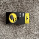 Černý papírový obal na produkt s žlutým prvkem v pravé části. Na obalu je fotografie černého pedálu s kabelem a text KORG PS-3 PEDAL SWITCH. Obal je…