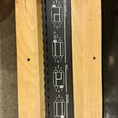 Černý úzký modul s bílým technickým schématem a nápisy na horní straně. Jsou zde viditelné texty: COMMON GROUND TAB, CHASSIS TOP, CHASSIS BOTTOM, HAL…