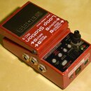 Červený kytarový pedál značky BOSS s nápisem Loop Station RC-3. Na horní straně jsou bílé šipky s označením INPUT A (MONO), INPUT B (MONO), OUTPUT A…