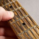 Detail hředu strunového nástroje s tmavým, žilnatým dřevěným hmatníkem a kovovými pražičkami. Na hmatníku jsou vidět dvě kulaté černé otvory pro ladi…