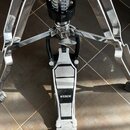 Detail chromovaného stojanu s pedálem. Na bílé části pedálu je černý nápis BRASIX. Povrch pedálu vykazuje známky opotřebení a znečištění.