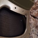 Detailní záběr na část reproduktoru s kovovým rámem v béžové barvě a olivově zeleným magnetem. Na černé membráně je viditelná bílá číslice 3. Povrch…