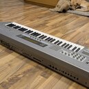 Stříbrný digitální klavír s černými a bílými klávesami. Na přední straně je viditelný nápis KORG Z1 a malý displej. Nástroj má v horní části řadu tla…