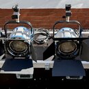 Čtyři stejné reflektory s modrými detaily na kovovém rámu. Každý reflektor má čtyři černé klapky pro směrování světla a horní úchyt s upevňovacím mec…