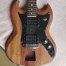 Elektrická kytara s přírodním dřevěným povrchem a černým pickguardem. Nástroj má dva humbuckery, dvě otočné potenciometry a jeden přepínač. V dolní č…