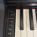 Detailní záběr na klávesy a ovládací panel černého digitálního piana. Na levém panelu jsou tlačítka s nápisy DEMO/SONG, FUNCTION, PIANO/VOICE, METRON…