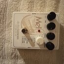 Bílý kytarový efekt s nápisy electro-harmonix NEW YORK CITY, USA a Mel tape replay machine. Zařízení má čtyři černé otočné knoflíky s popisky DRY, VO…