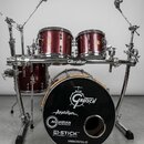 červená bubnová sada s kovovým hardwarem značky Gibraltar. Na basovém bubnu je černý přední zástěrník s logem Gretsch a nápisy Anatolian, AQUARIAN DR…