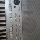 Detailní pohled na ovládací panel stříbrného digitálního klavíru s černými klávesami. Panel obsahuje různé sekce tlačítek, včetně „MULTI PAD CONTROL“…