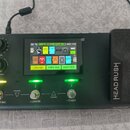 Černý kytarový procesor značky HEADRUSH s integrovaným pedálem. Zařízení má digitální displej, na kterém je vidět text META 10 FADE LIVE SO a tlačítk…
