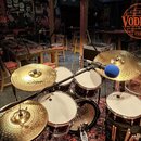 Fotografie zobrazuje bicí sadu v tmavě červené barvě s bílými blány značky Evans. Sada obsahuje tři bubny a tři činely značky Zildjian. Celý komplet…