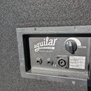 Detail zadní strany basového komba s šedým povrchem. Je zde logo „aguilar AMPLIFICATION Amplify Yourself®“, ovládací prvek s nápisem „TWEETER“ a tři…