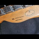 Detail zadní strany hlavy kytary z přírodního dřeva s kovovými ladičkami. Je zde vidět logo Fender v oválu s nápisem SPECIAL EDITION a hvězdičkou. Dá…