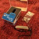 Na fotografii je kytarový snímač s chromovaným krytem a černým kabelením. Vedle něj je modré originální krabička s nápisy „Seymour Duncan“, „Vintage…
