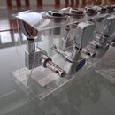 Sada chromovaných ladících kolínek umístěná v průhledném plastovém držáku. Kolínka mají kovové tělo a plastové knoflíky. Na některých z nich jsou vid…