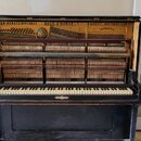 Černý piano v otevřeném stavu s viditelným vnitřním mechanismem a strunami. V horní části je zlatý nápis GOLD MEDALS, DIPLOMAS KOCH & KORSELT HIGHEST…