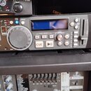 Fotografie zachycuje rackové zařízení, konkrétně digitální CD/MP3 přehrávač v šedé barvě. Na předním panelu jsou vidět ovládací prvky, displej a nápi…