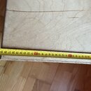 Fotografie zachycuje detail světlého dřevěného povrchu s viditelnou strukturou slátek. Na povrchu jsou patrné dvě tenké rýhy. Přes hranu předmětu je…